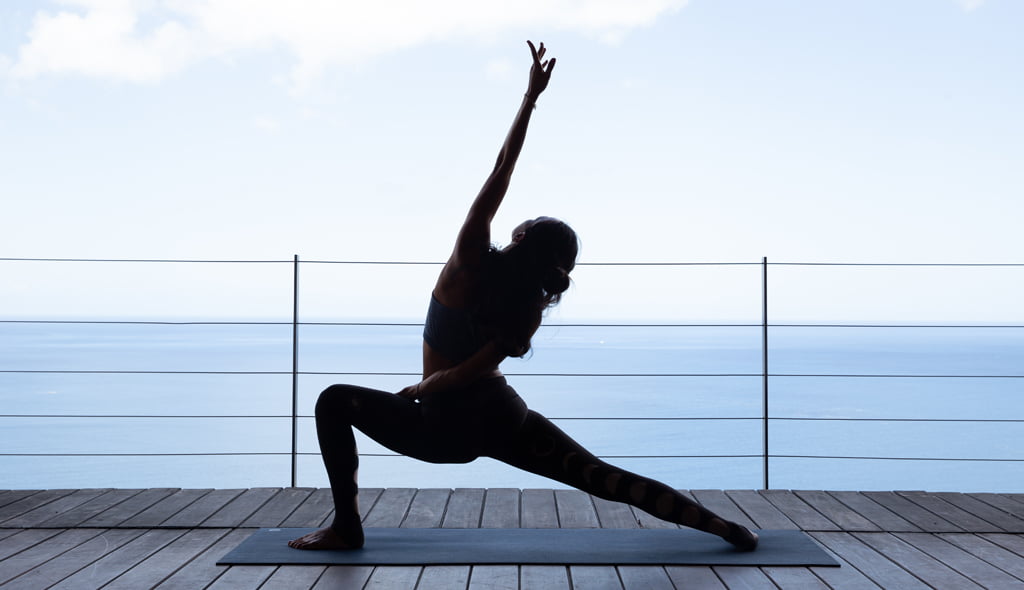 A woman practising yoga at Cosmos St Lucia luxury villa while overlooking the sea