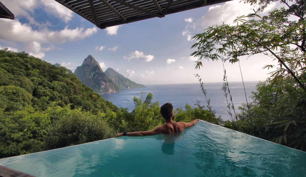 A man relaxes in the plunge pool at the Lodge, Cosmos St Lucia, looking over the caribbean Sea to the Pitons