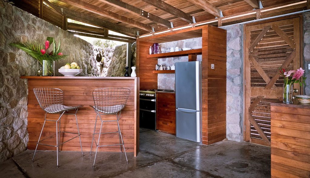 The kitchen area inside the Lodge at Cosmos St Lucia features a bar and stools for eating, a fridge freezer and oven
