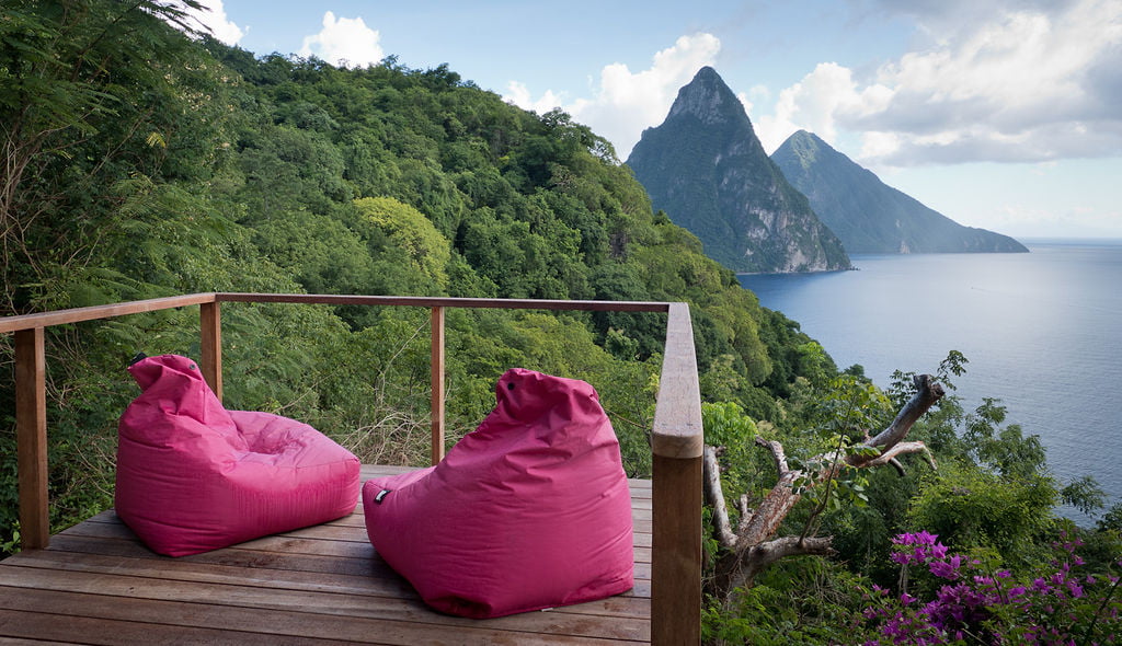 two pink bean bags on the sundeck at the Lodge, Cosmos St Lucia, look over the lush green hillside and the Pitons