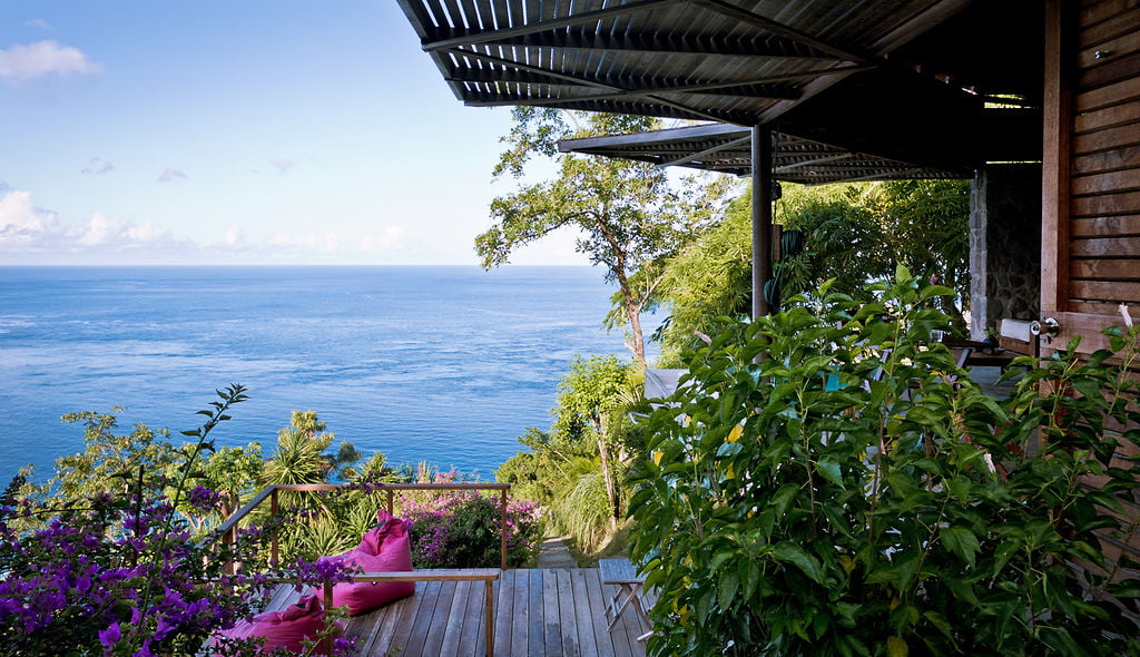 The Lodge at Cosmos St Lucia features a wooden sun deck overlooking the Caribbean Sea and the Pitons