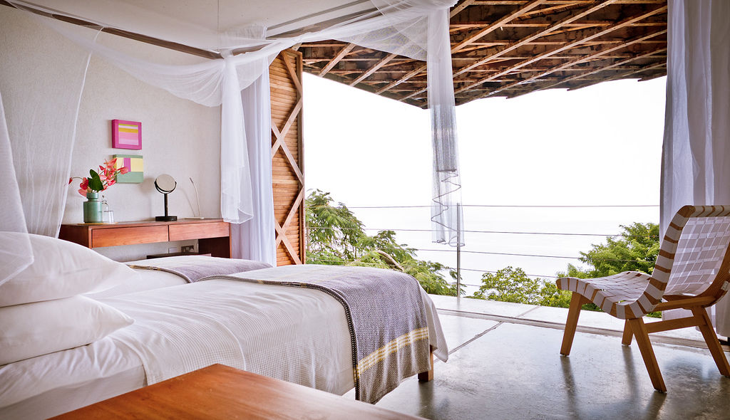 A twin bedroom in the Villa at Cosmos St Lucia, showing an easy chair, a desk and the underside of the wooden Cantilever structure that forms the heart of the building