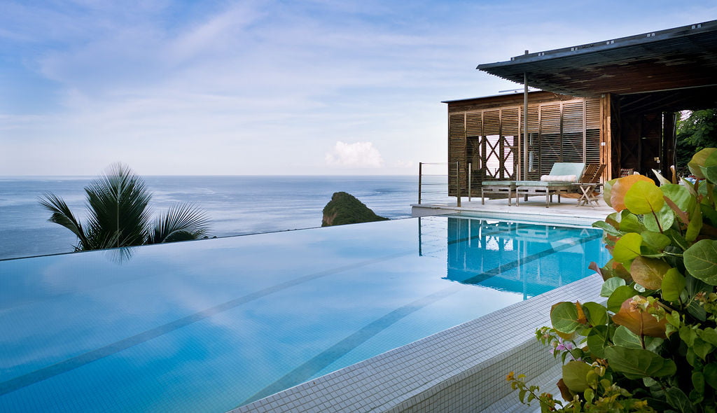 Sun terrace and infiinity pool with plants in the foreground and the carribean sea in the background