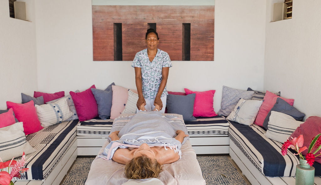 A spa therapist gives a foot massage to a woman lying on a massage table