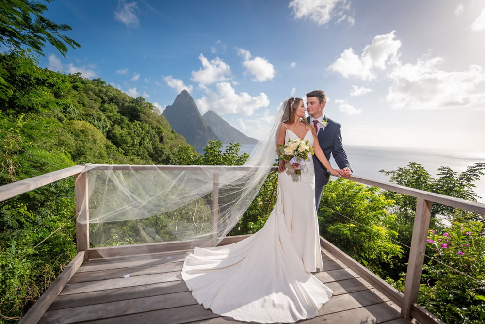 A newly married couple embrace on the The Lodge deck with the Pitons in the background