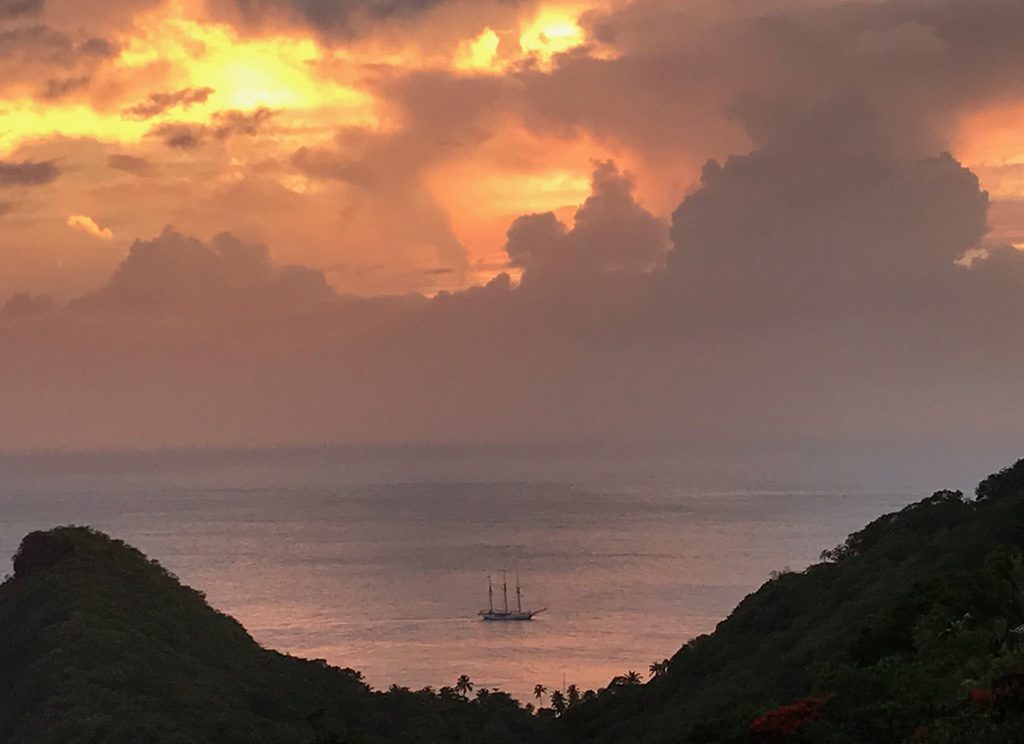A yacht on the Carribean sea, infront of a peach sunset sky