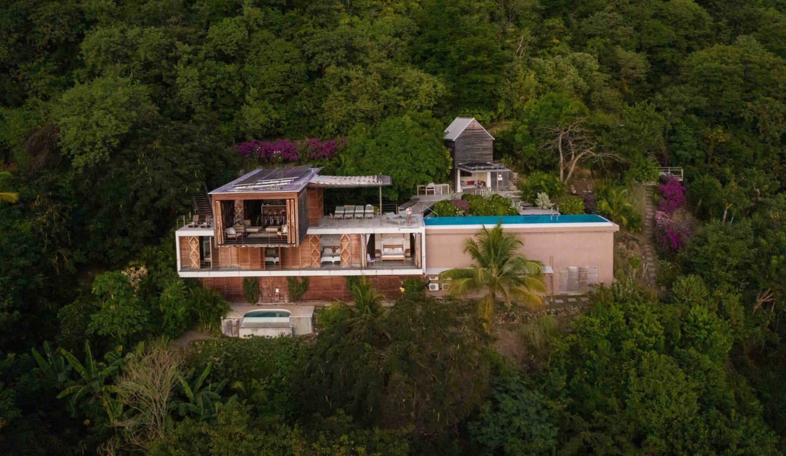 Aerial view of eco luxury villa Cosmos St Lucia featuring open air architecture, perched on a hillside surrounded by lush green vegetation on a hillside near Mamin, St lucia
