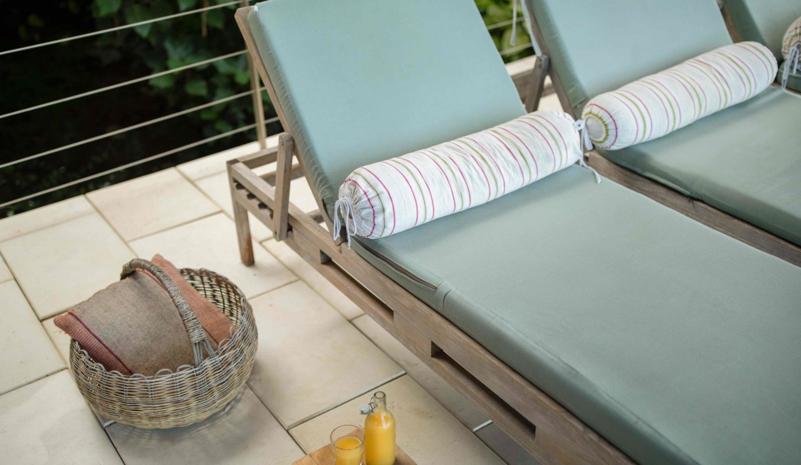 Press orange juice on a tray beside sunloungers on the terrace at Cosmos St Lucia