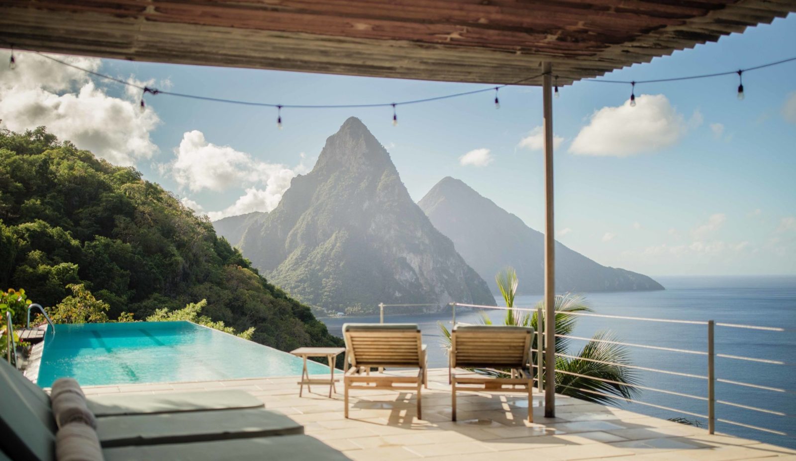 Sunloungers on the terrace at Cosmos St Lucia are shaded by a wooden canopy and look out onto the Pitons