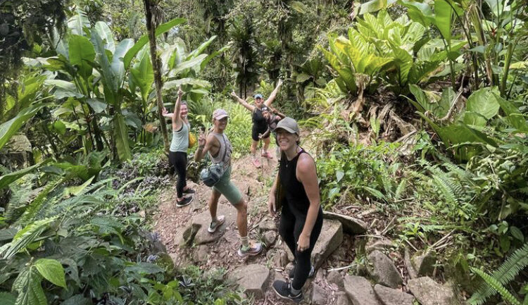 Four smiling girls wearing sportswear turn to face the camera and express excitement as they pause their hike for a photo to commemorate their achievement hiking Gros Piton St Lucia
